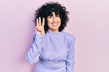 Young middle east woman wearing casual clothes showing and pointing up with fingers number three while smiling confident and happy.