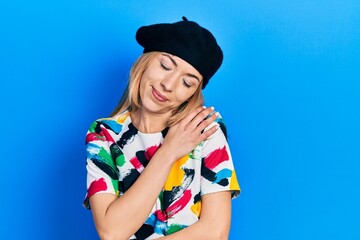 Young caucasian woman wearing french look with beret hugging oneself happy and positive, smiling confident. self love and self care
