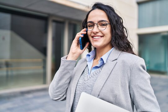 Young hispanic woman executive talking on the smartphone at street