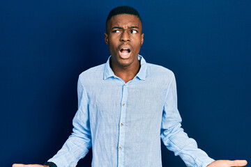 Obraz premium Young african american man wearing casual clothes crazy and mad shouting and yelling with aggressive expression and arms raised. frustration concept.