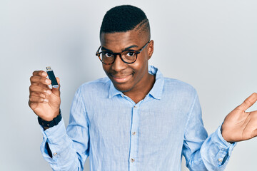 Young african american man holding removable memory usb celebrating achievement with happy smile and winner expression with raised hand