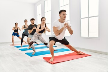 Fototapeta na wymiar Group of young hispanic people concentrate training yoga at sport center.