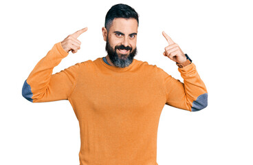 Fototapeta premium Hispanic man with beard wearing casual winter sweater smiling pointing to head with both hands finger, great idea or thought, good memory