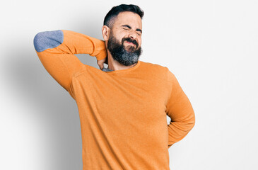 Naklejka premium Hispanic man with beard wearing casual winter sweater suffering of neck ache injury, touching neck with hand, muscular pain