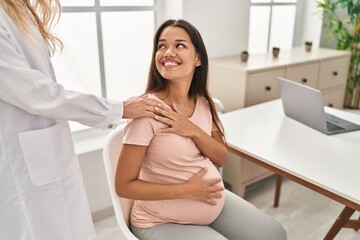 Young latin woman pregnant and doctor together at clinic