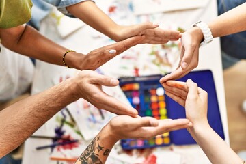 Group of people doing heart sign with hands together at art studio.