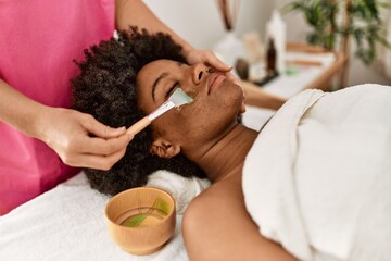 Young african american woman having facial treatment at beauty center
