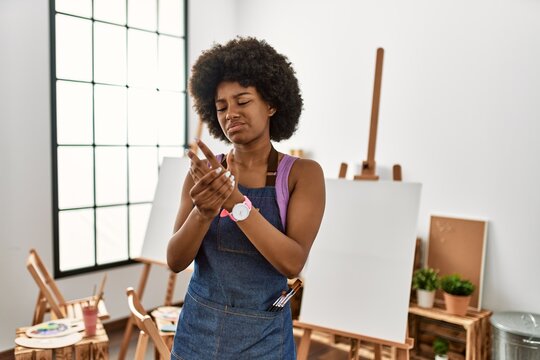Young african american woman with afro hair at art studio suffering pain on hands and fingers, arthritis inflammation - Powered by Adobe
