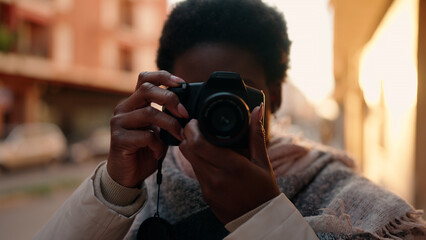 Young african american woman using professional camera at street