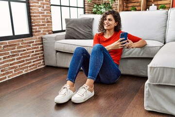 Young latin woman smiling confident using smartphone at home