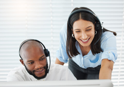 Need some help. Shot of a handsome young salesman sitting in the office and wearing a headset while getting help from his manager.