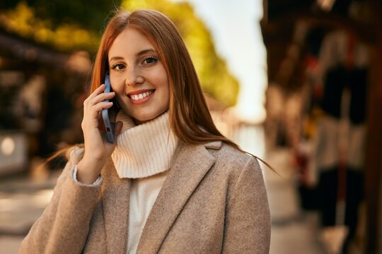 Young redhead girl smiling happy talking on the smartphone at the city.