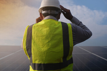 The back of an engineer wearing a helmet is checking the operation of a renewable energy concept...