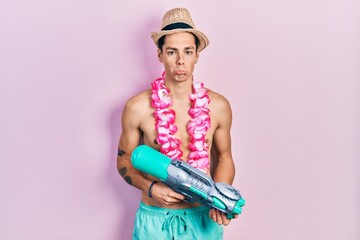 Young hispanic man wearing swimsuit and watergun depressed and worry for distress, crying angry and...