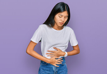 Beautiful young asian woman wearing casual white t shirt with hand on stomach because indigestion, painful illness feeling unwell. ache concept.