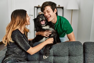 Young caucasian couple smiling happy hugging dog at home.