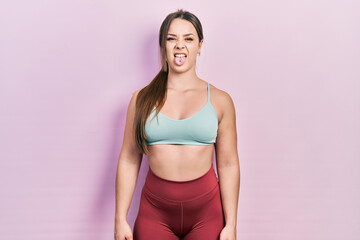 Young hispanic girl wearing sportswear sticking tongue out happy with funny expression. emotion concept. © Krakenimages.com