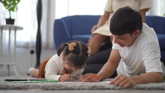 Portrait enjoy happy love asian family father and mother with little asian girl learn and study on table.Mom and dad with asian girl writing with book make homework in homeschool at home.Education	