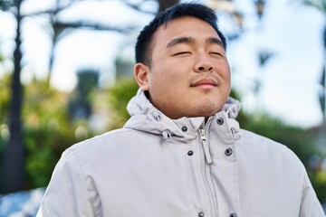 Young chinese man breathing standing at park