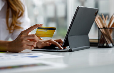 Close up of Young Asian women using a credit card and tablet laptop at the home office for buying online shopping or payment, buying and online shopping concept.