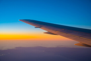 View of the wing of an airplane during flight from the window at sunset.