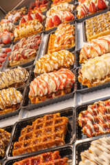 Delicious traditional Liege waffles with colorful toppings on display in a store window in Brussels, Belgium. Sugary desserts. Typical Belgian sweet food.