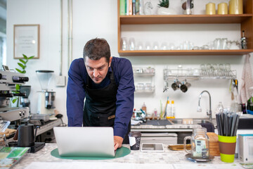 happy man barista using laptop for take order from customer in coffee shop.