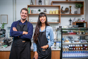 Portrait of smiling owner man standing at his cafe. Coffee owner standing with apron in coffee shop to welcome customer.