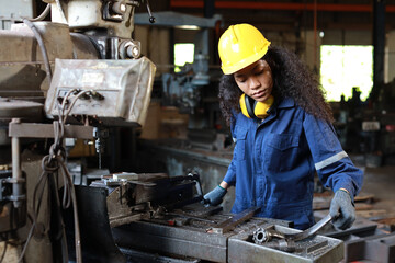 Fototapeta premium Technician engineer or worker woman in protective uniform with safety hardhat maintenance operation or checking lathe metal machine at heavy industry manufacturing factory. Metalworking concept