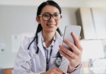 Following up with a patient. Cropped shot of a young female doctor sending a text while working in the hospital.