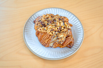 Roasted Hazelnut Coffee Croissant is a delicious homemade bakery on a wooden table. Traditional French breakfasts crispy croissants baked pastries are favorited worldwide.