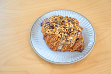 Roasted Hazelnut Coffee Croissant is a delicious homemade bakery on a wooden table. Traditional French breakfasts crispy croissants baked pastries are favorited worldwide.