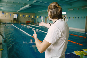 Coach practise with swimmer in the indoor swimming pool