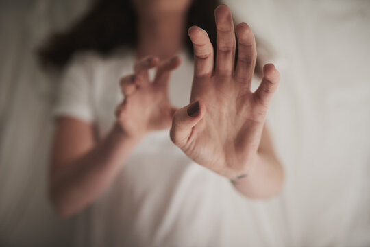 First do no harm. High angle shot of an unidentifiable young woman holding up her hands in a defensive gesture while lying in bed.