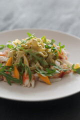 Fettuccine pasta with crab and arugula on black wood table
