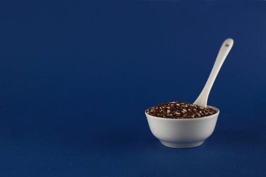 bowl of beniseed and linseed mix and spoon isolated on blue background
