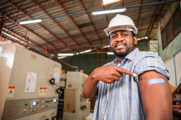 African workers  pointing at his arm with a bandage after receiving the covid-19...