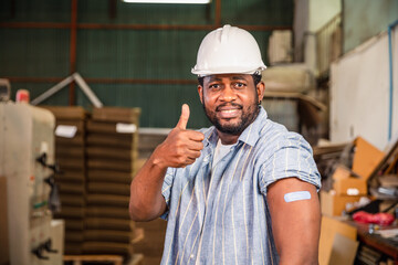 African workers  pointing at his arm with a bandage after receiving the covid-19...