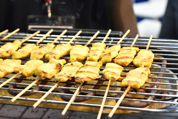 Pork satay with peanut sauce on a hot grill