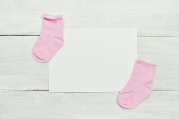 Obraz na płótnie Canvas baby socks with blank paper on white wooden background.
