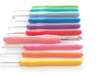 Colorful crochet hooks in different sizes for knitting isolated on white background in soft focus