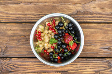 Various berries in a bowl on a wooden table with copy space. Healthy food, vitamins, antioxidants.