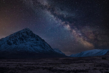 Obraz na płótnie Canvas Majestic vibrant Milky Way composite image over landscape of snowcapped Winter mountains in Scotland