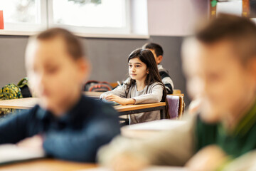 A schoolgirl following lecture with classmates in elementary school.