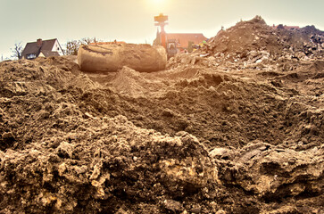 Ground view over the sandy subgrade of a construction site with an excavated earth tank and an...