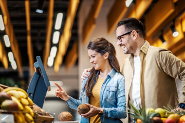 A happy couple measuring coconut at the supermarket.