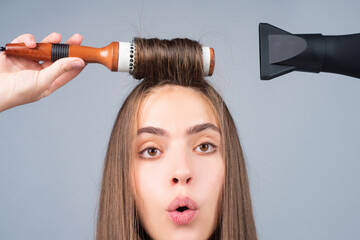 Funny woman close up face combing hair and dryer hair with hairdryer. Portrait of female model with...