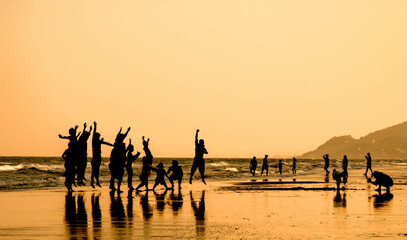 Silhouette photo of the people jumping on the beach at sunset