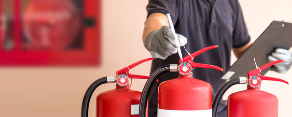 Close up fire extinguisher and firefighter checking pressure gauge level for protection and prevent and safety rescue and use of equipment on fire training concept.