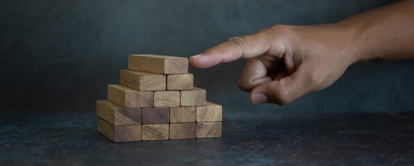 Hand push to prevent wooden block tower stack in pyramid not crash or fall. concept of prevention...